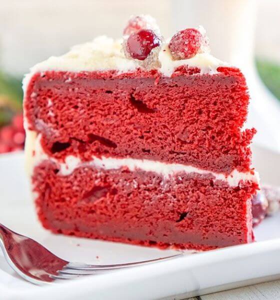 Red velvet Christmas cake on white plate with cranberries on top