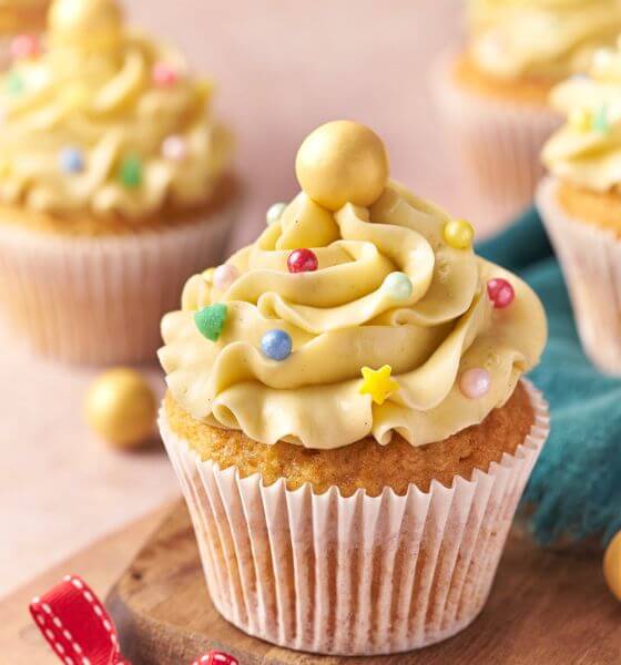 Eggnog flavored cupcakes with decorative frosting and gold and colored beads