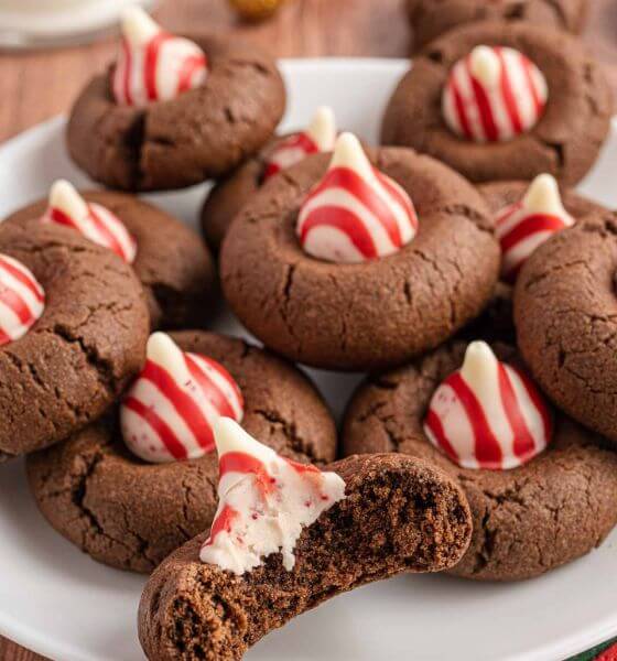 Chocolate cookies with peppermint hershey kisses on top on a white plate