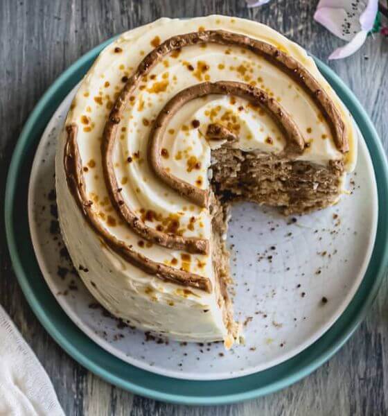 Cinnamon roll cake with slice cut out of it on a blue and white plate