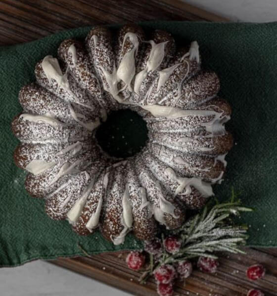 Gingerbread bundt cake with white frosting on a green towel