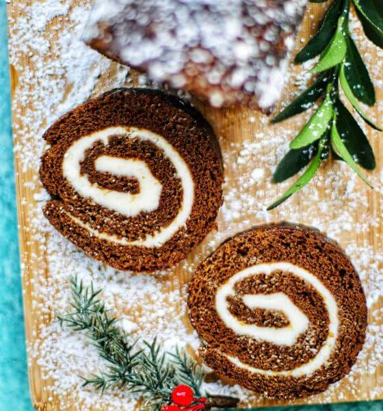 Gingerbread cake roll on powdered wood surface and greenery