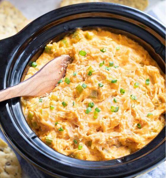 Buffalo chicken dip in crockpot with wooden spoon