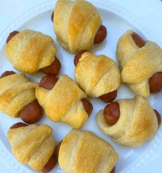 Little smokies in crescent rolls (pigs in a blanket) on a white plate.