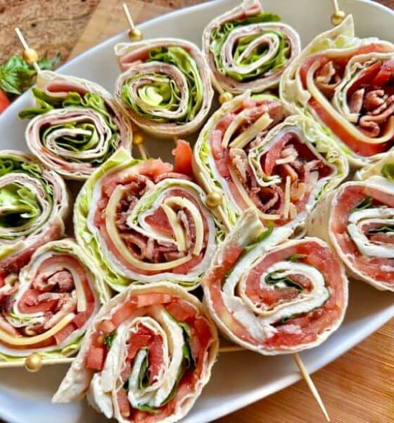 Turkey, bacon and lettuce pinwheels on white platter.