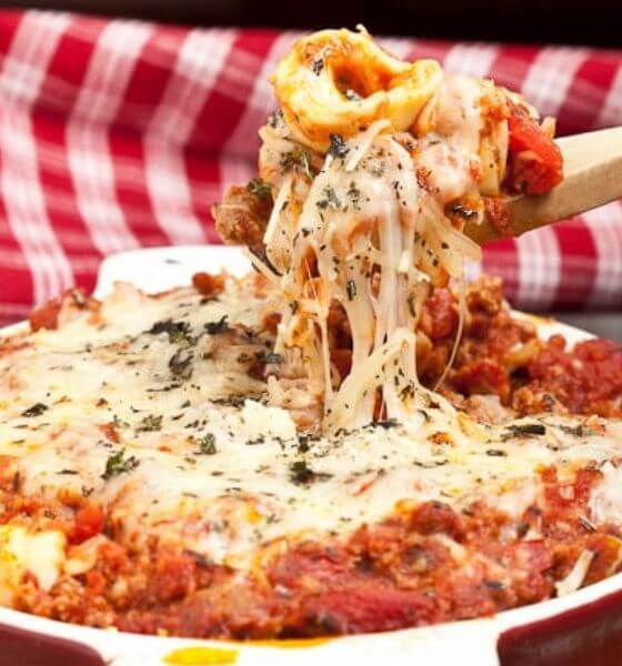 Tortellini casserole in white round casserole dish with wooden spoon