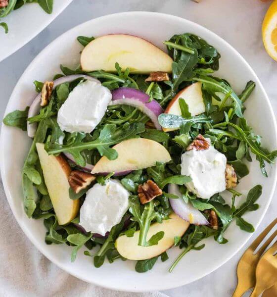 Apple arugula salad with pecans in white bowl