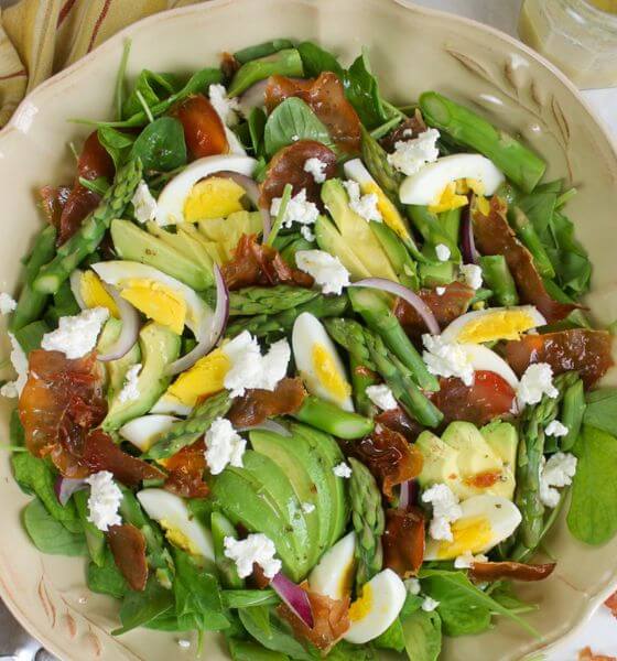 Spring salad with asparagus, eggs, and avocado in white bowl