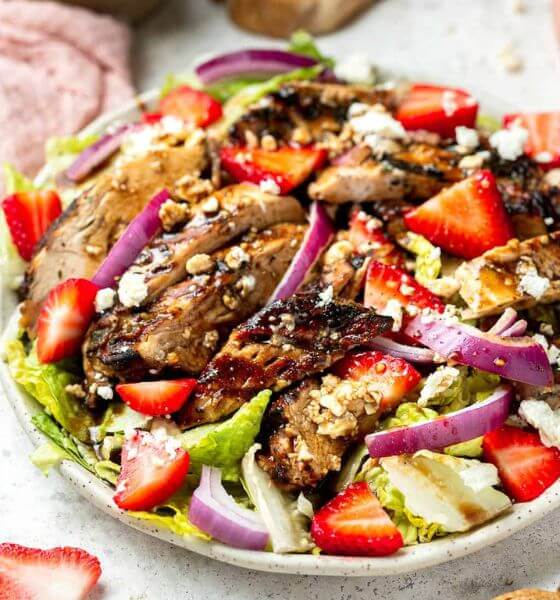 Balsamic grilled chicken salad with strawberries and onions in white dish