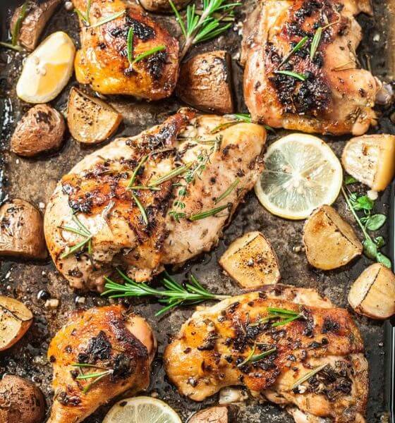 Roasted chicken chicken with garlic potatoes and slices of lemon on a baking sheet