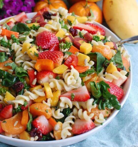 Pasta salad in white bowl with strawberries and vegetables