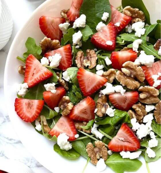 Strawberry salad in greens with feta cheese in white dish