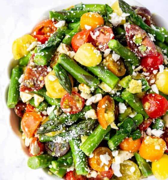 Asparagus, tomatoes, avocado salad in white bowl