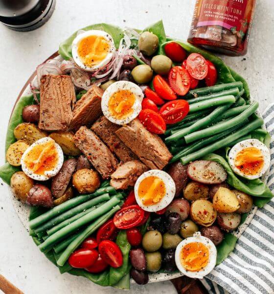 Salad with eggs, tuna, green beans, tomatoes and olives in glass dish