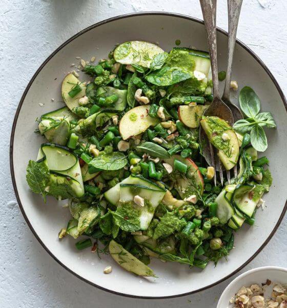 Zucchini salad with green beans in white dish with fork and spoon