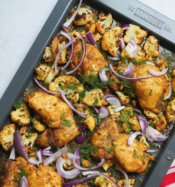 Chicken, cauliflower and red onions on a baking sheet