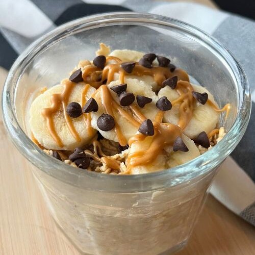 overnight oats in glass jar with banana slices and peanut butter and chocolate chips on top