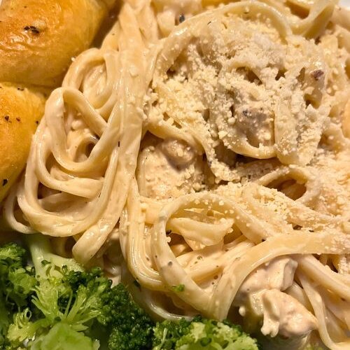 Chicken Fettuccine with Alfredo on white plate with broccoli and breadstick