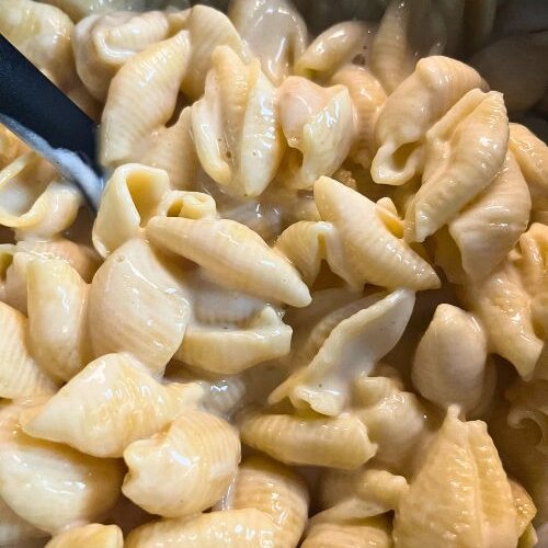 Pasta shells and cheese in Instant Pot with black spoon