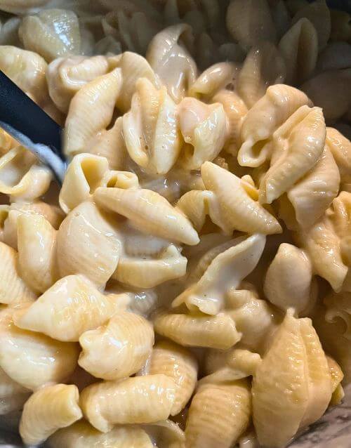 Pasta shells and cheese in Instant Pot with black spoon