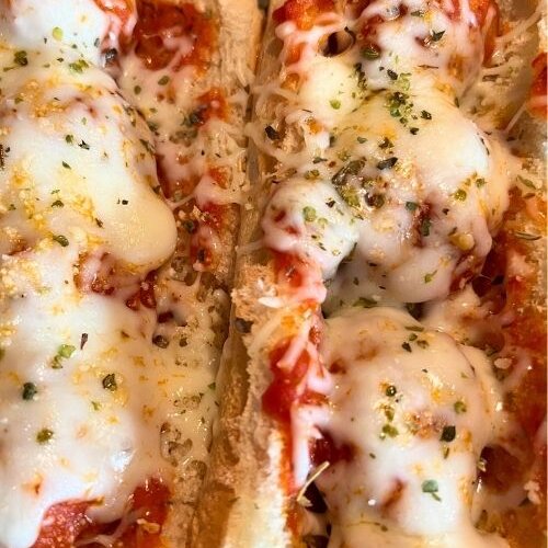 two meatball subs with mozzarella cheese on top