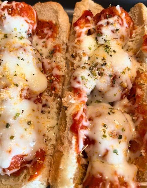 two meatball subs with mozzarella cheese on top