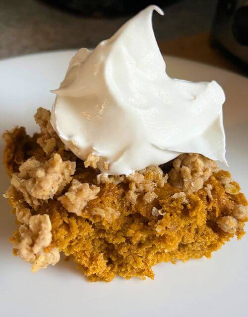 Pumpkin cake with whipped cream on white plate